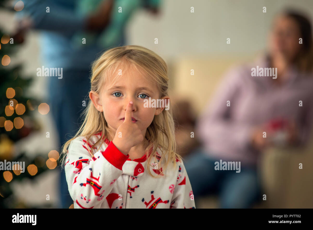 Portrait of a playful young girl touching her nose. Stock Photo