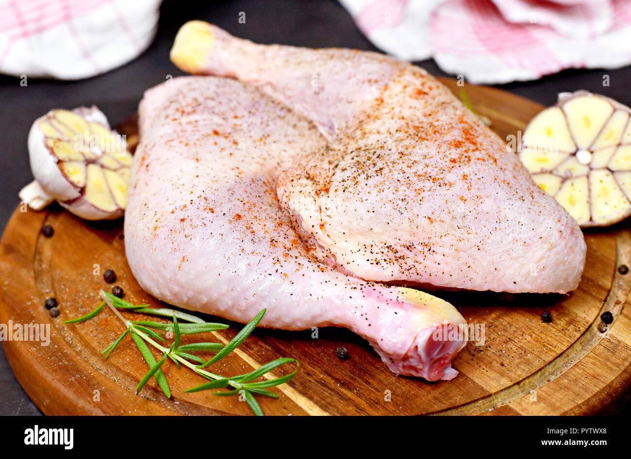 Delicious raw chicken legs or drumsticks on a wooden cutting board. Rustic preparation scene with garlic and raw meat. Stock Photo