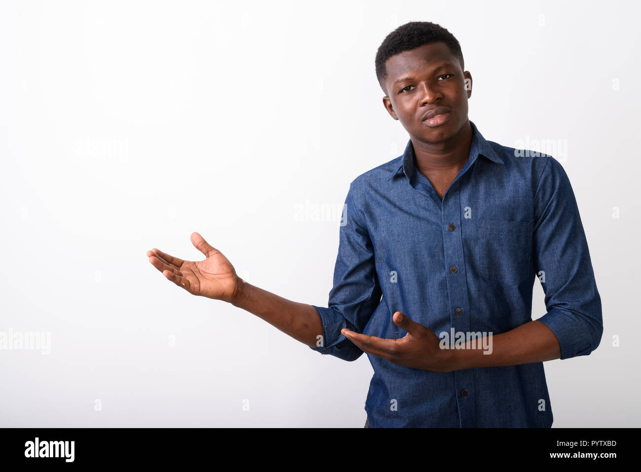 Studio shot of young black African man showing something against Stock Photo