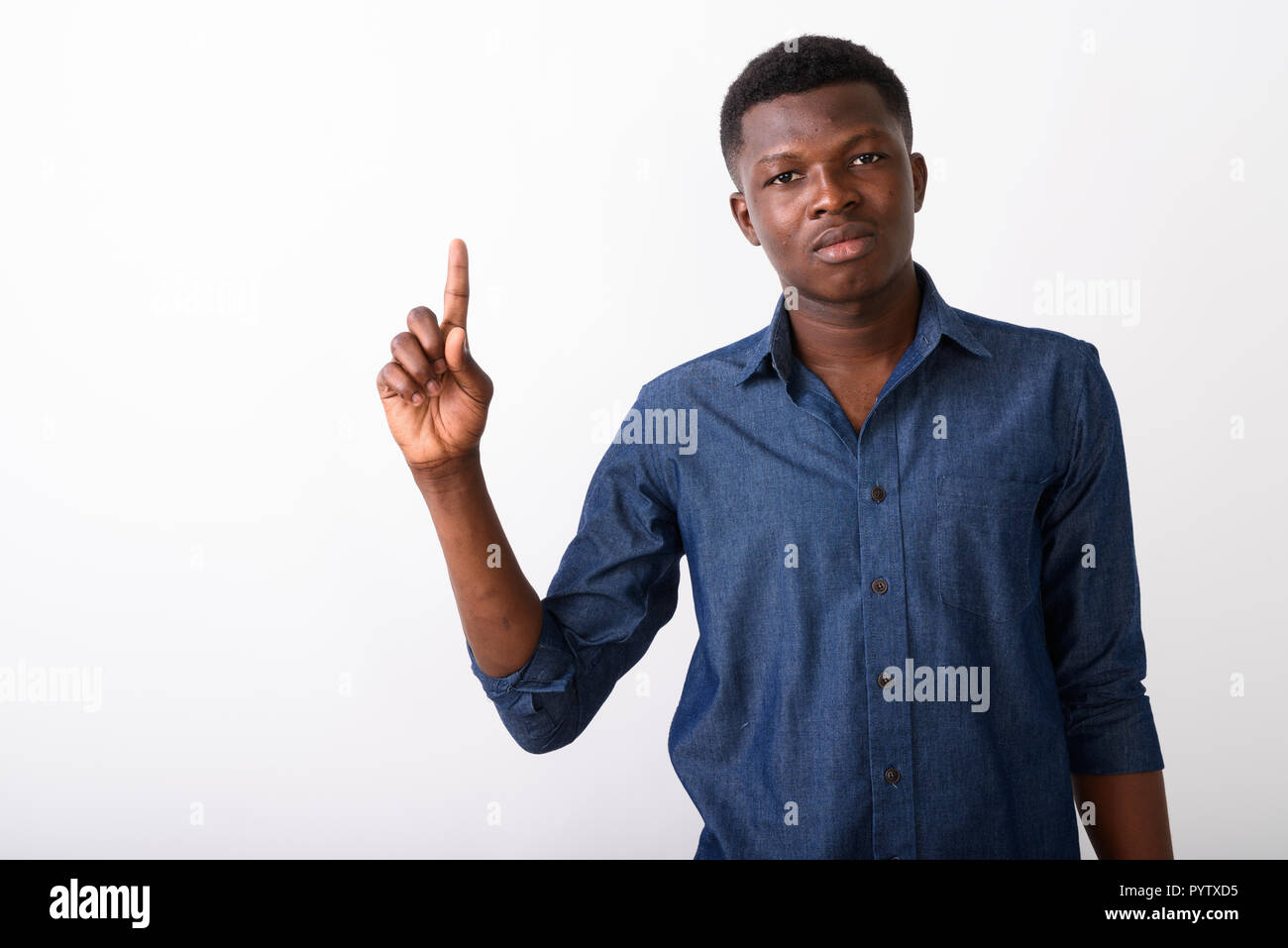 Studio shot of young black African man pointing finger up agains Stock Photo