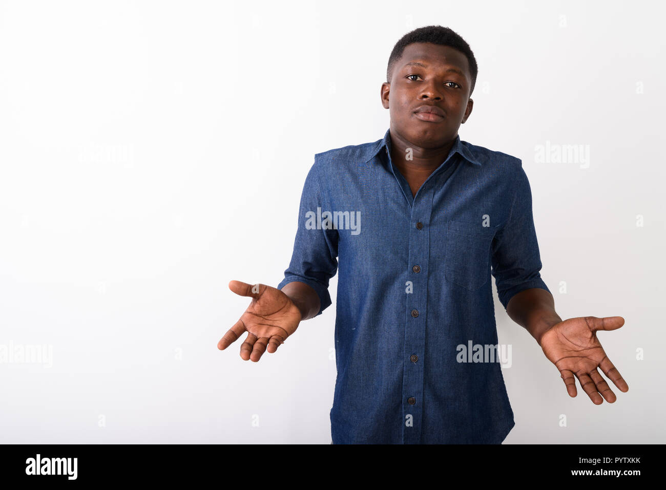 Studio shot of young black African man looking confused against  Stock Photo