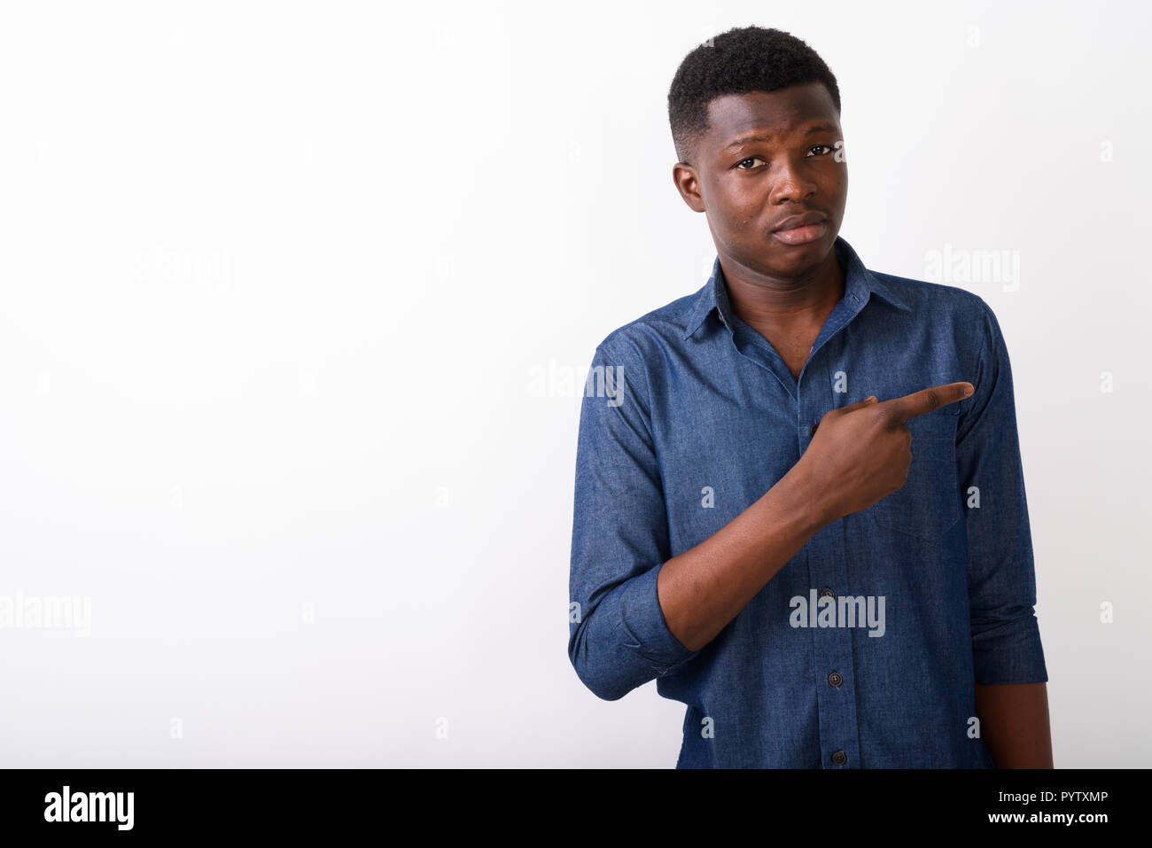 Studio shot of young black African man pointing to the side agai Stock Photo