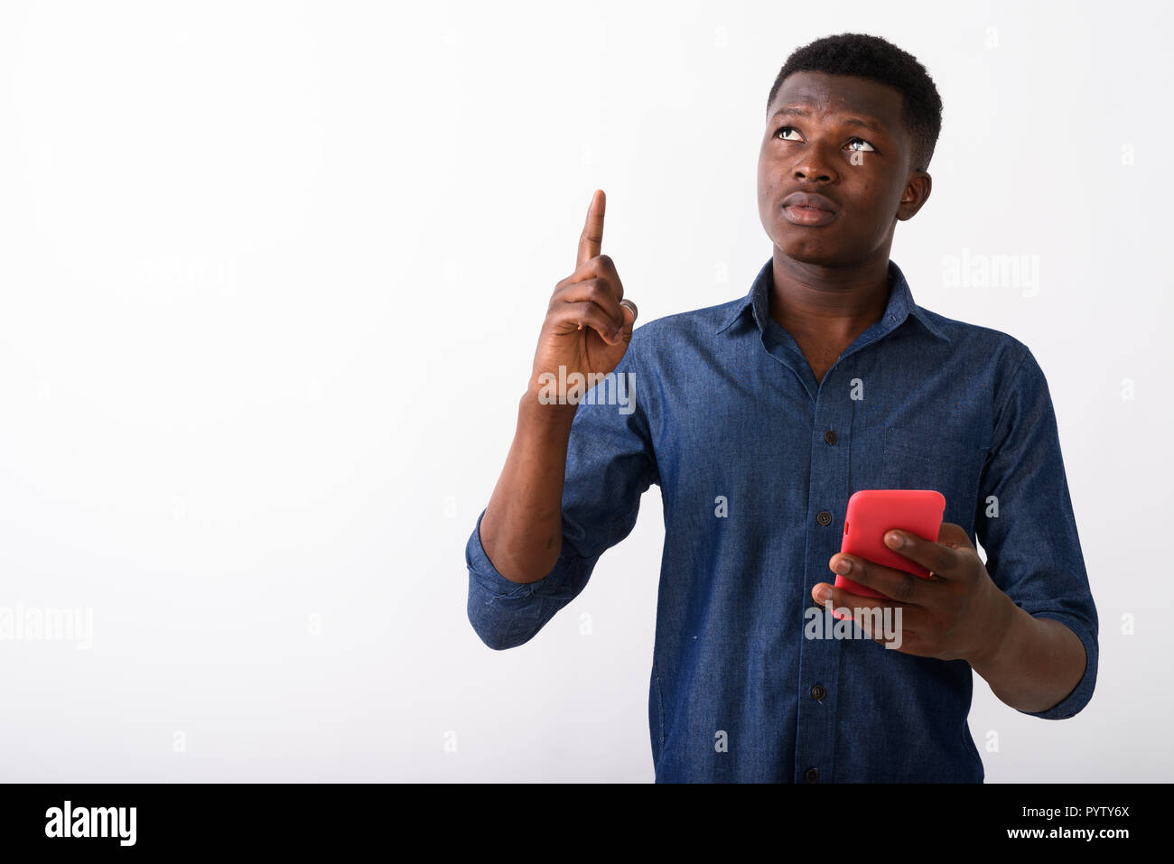 Studio shot of young black African man thinking while pointing f Stock Photo