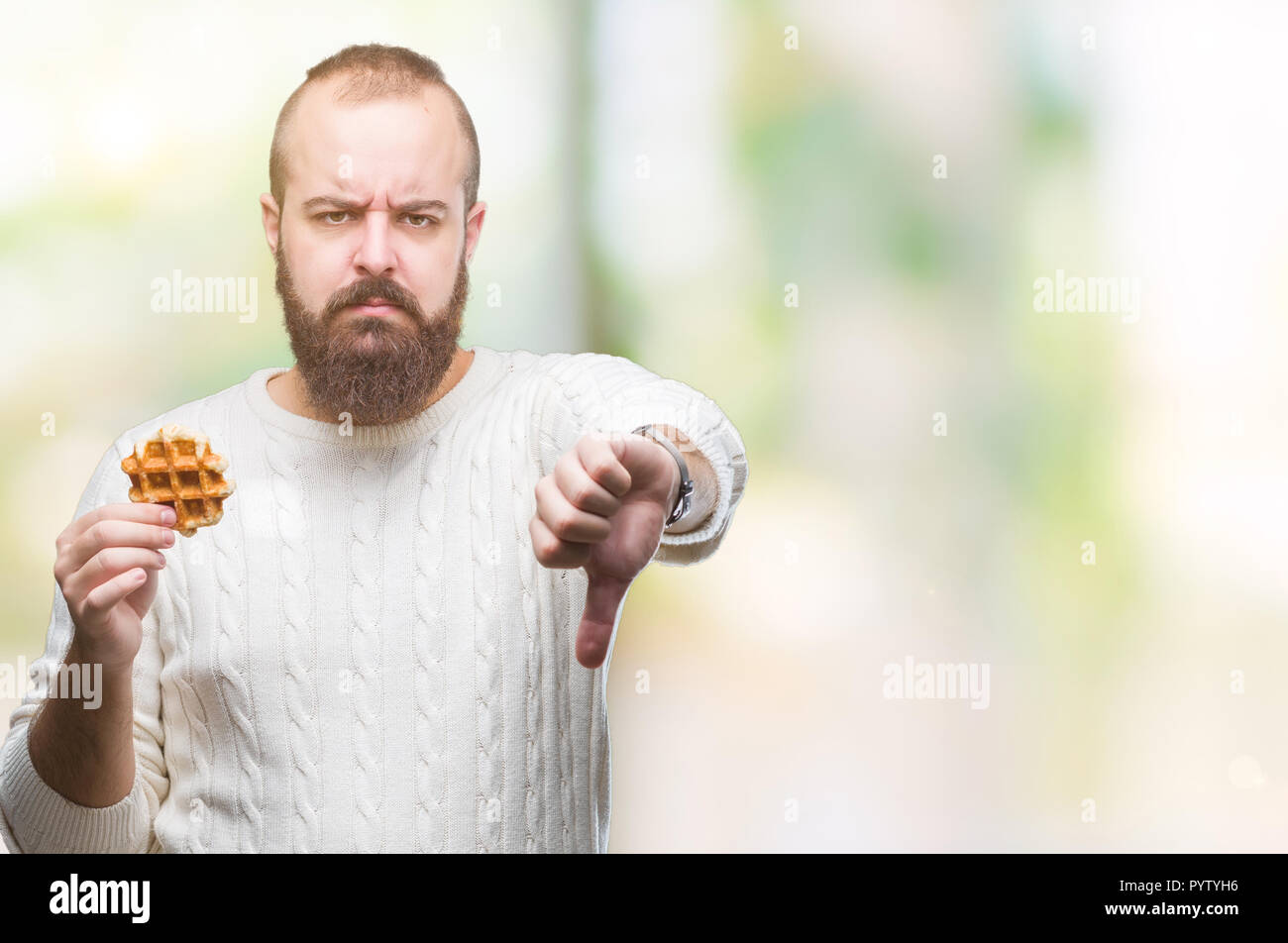 Young caucasian hipster man eating sweet waffle over isolated ...