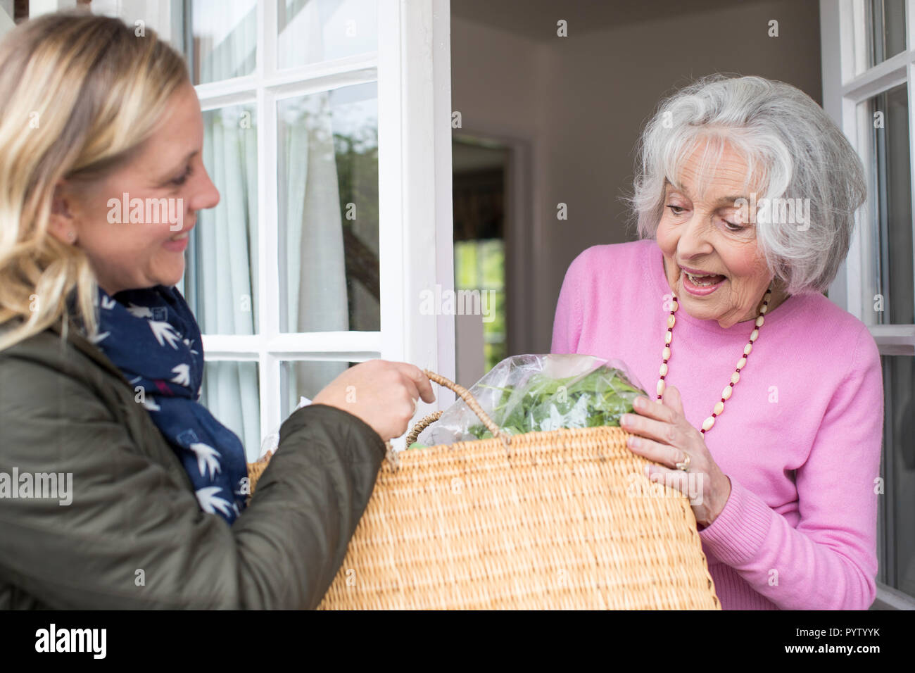 Female Neighbor Helping Senior Woman With Shopping Stock Photo