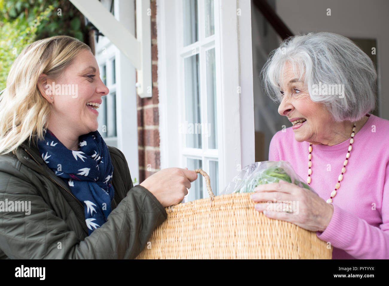 Female Neighbor Helping Senior Woman With Shopping Stock Photo