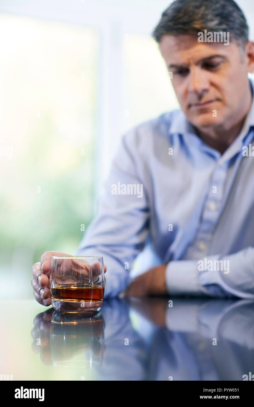 Unhappy Mature Man With Alchol Problem Holding Glass Of Whiskey At Home Stock Photo