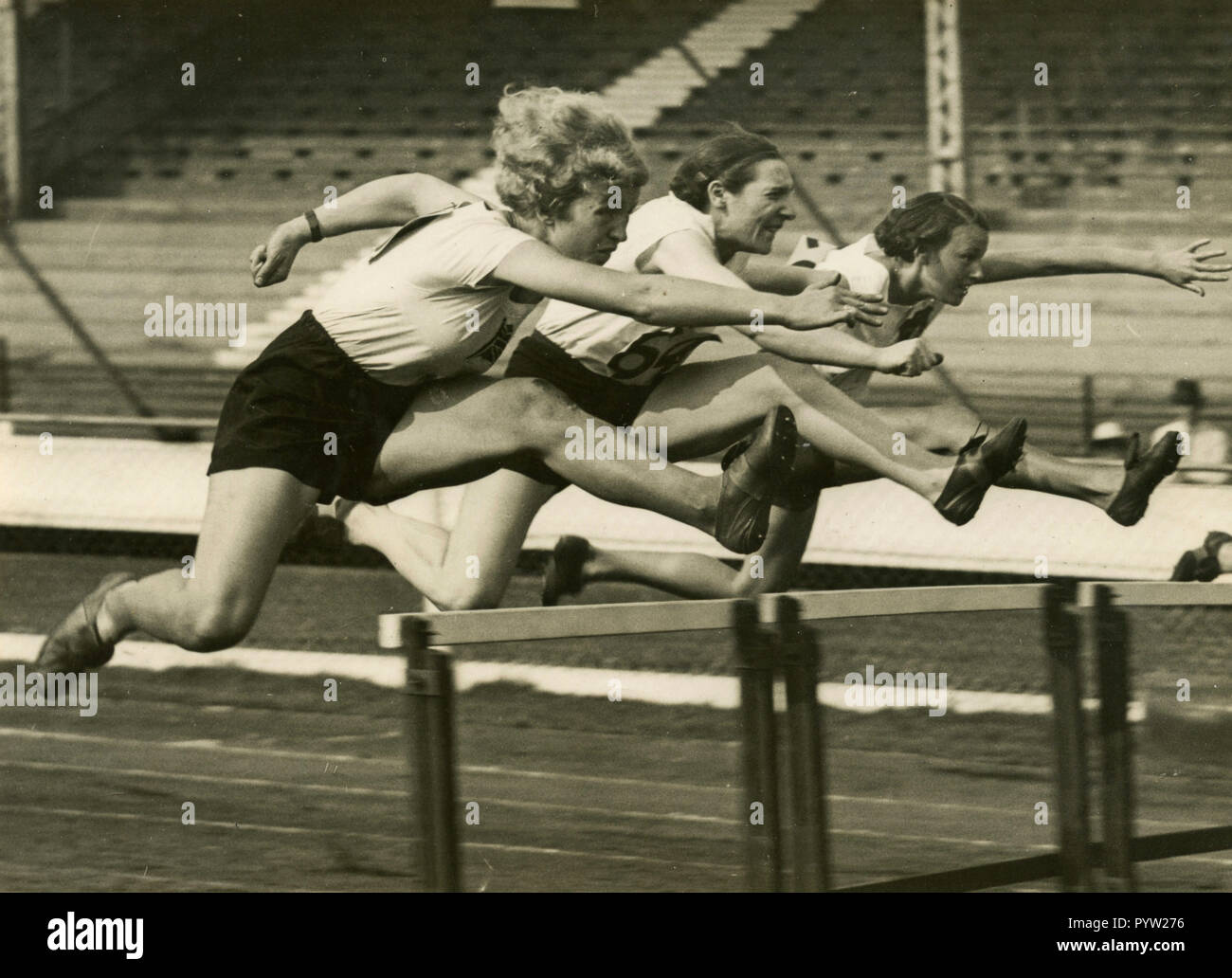 Women hurdle jump race, 1930s Stock Photo