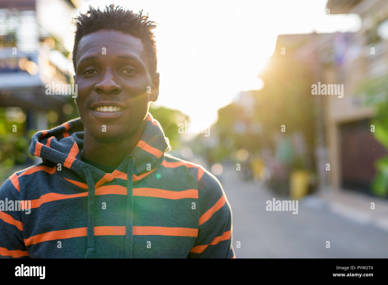 Close up portrait of young happy slim black African man smiling outdoors Stock Photo