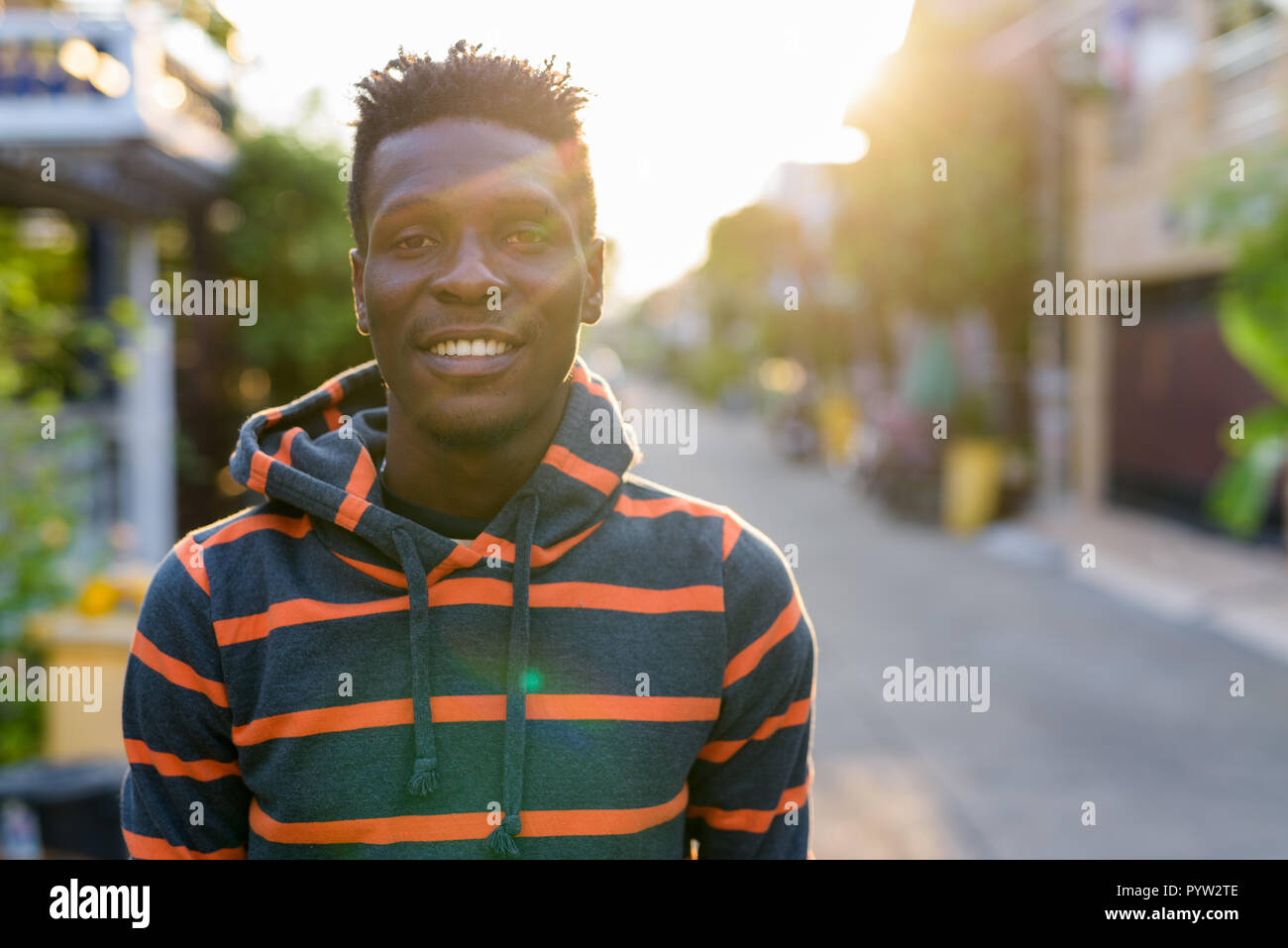 Young happy slim black African man smiling with sunlight beaming Stock Photo