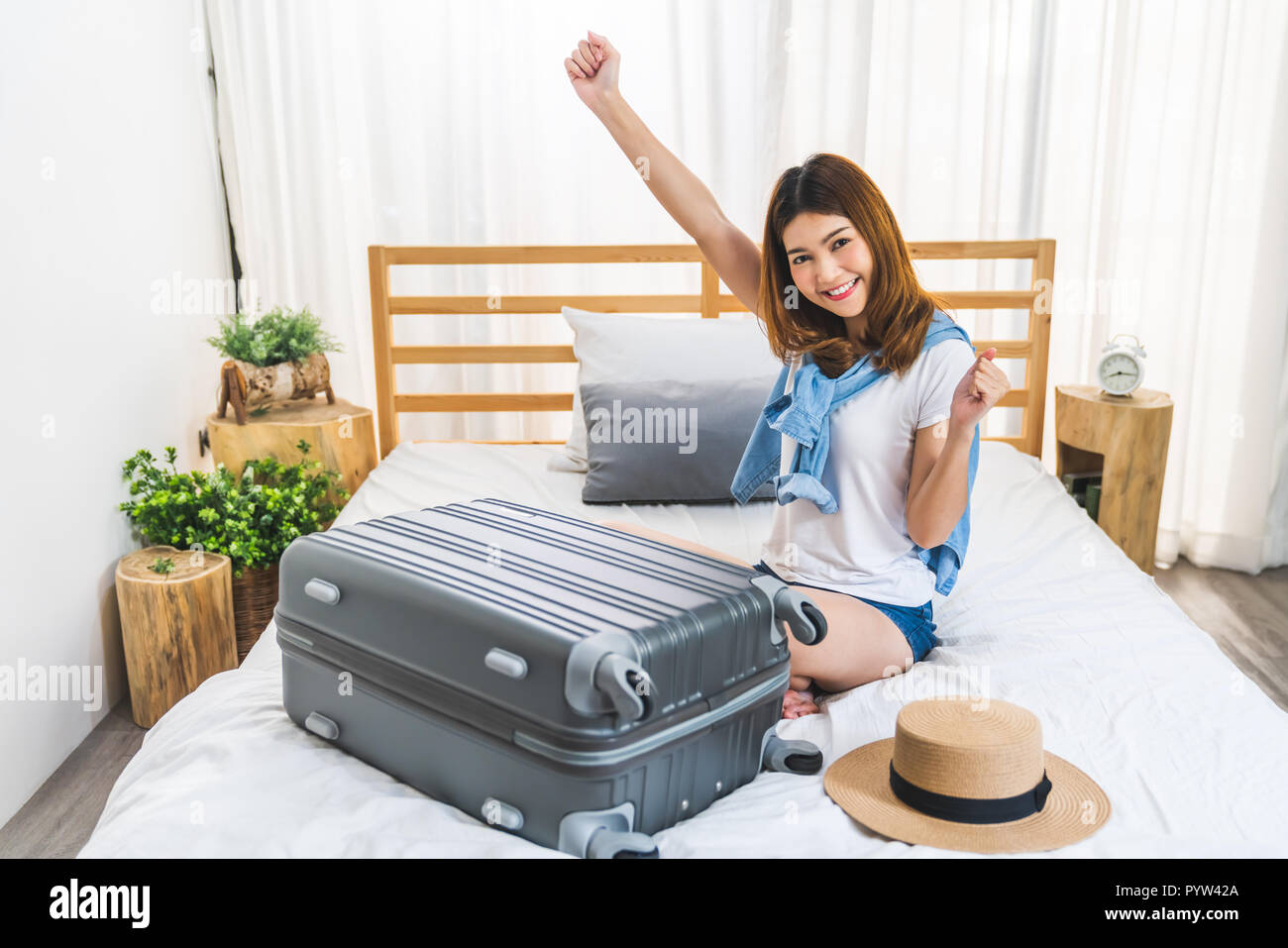 Young cute happy lovely Asian girl finished packing suitcase luggage on bed in bedroom, ready to go abroad solo trip. Asia traveler, Asian tourism Stock Photo