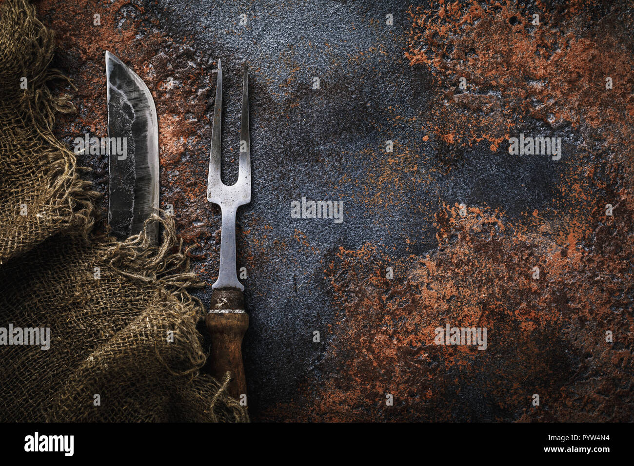 Knife and fork for meat on rusty table. Top view of vintage kitchen