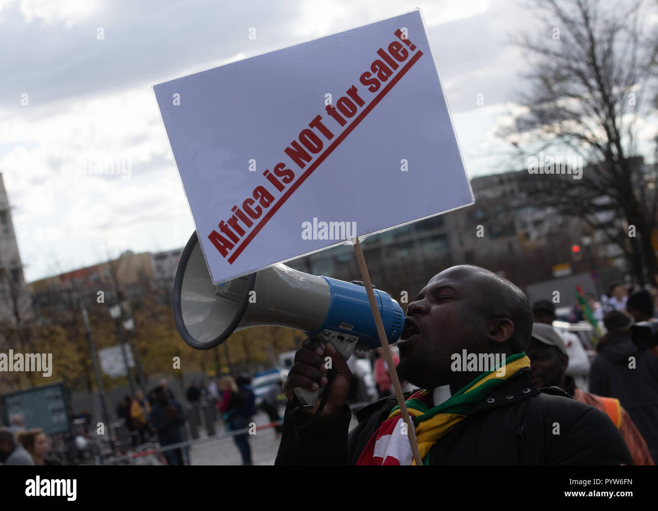 Berlin, Germany. 30th Oct, 2018. 'Africa is not for sale' is written on the poster of a demonstrator at the Brandenburg Gate. The reason for the protest is the Africa Conference at the Federal Chancellery. Credit: Paul Zinken/dpa/Alamy Live News Stock Photo