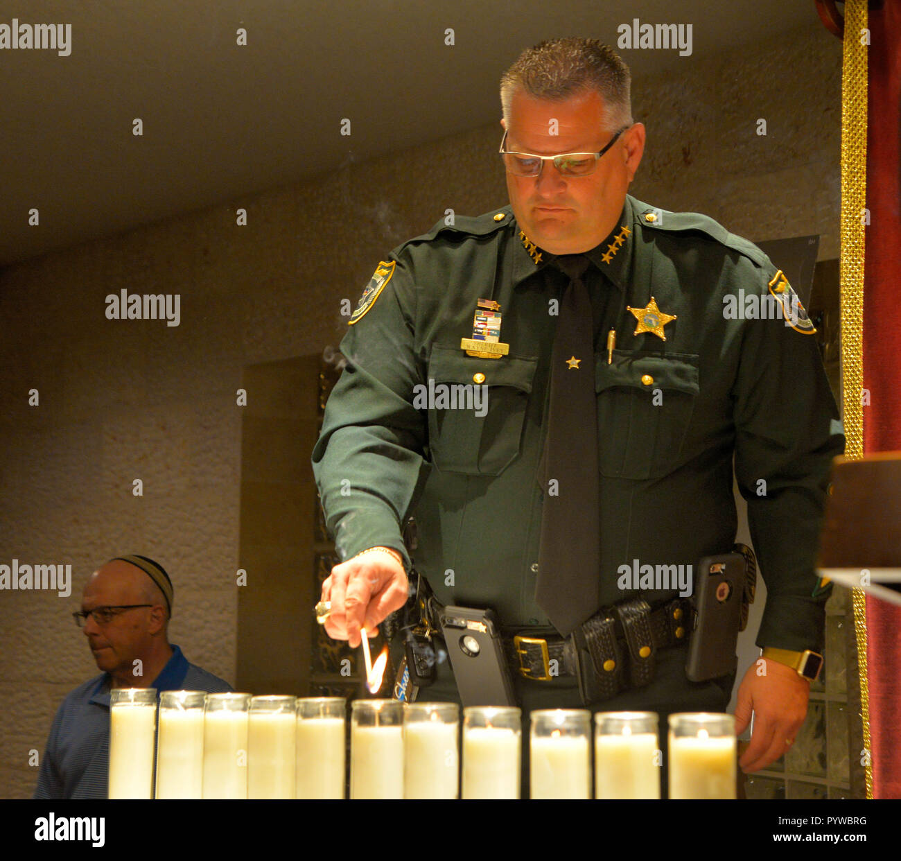 Satellite Beach, Florida, USA October 30, 2018. Rabbi Zvi Konikov with JewishBrevard Synagogue and Brevard County Sheriff Wayne Ivey attended a vigil remembering the 11 people killed at a Pittsburg synagogue. Sheriff Ivey stated that his office was committed to the safety of everyone attending religious events while the rabbi called for the people to ‘love thy neighbor. Ivey with others lit 11 candles to honor the 11 tragic deaths.  Photo Credit Julian Leek / Alamy Live News Stock Photo