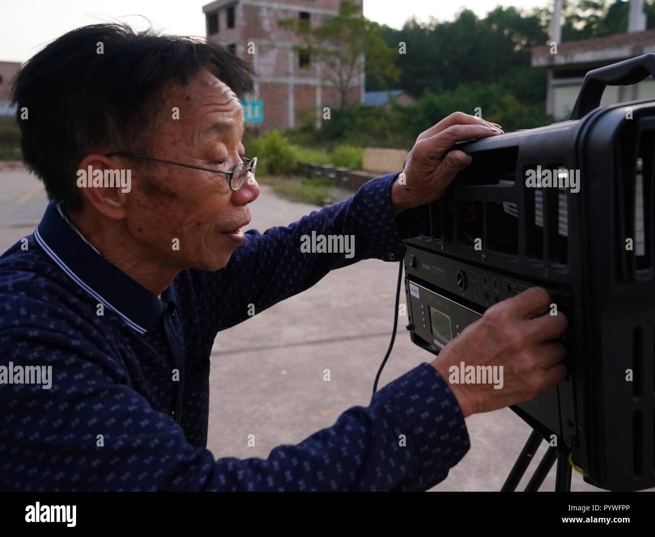 (181031) -- YUDU, Oct. 31, 2018 (Xinhua) -- Zeng Jilian, a 69-year-old movie projectionist, tests the movie projection facilities in Shanxia Village of Yudu County, east China's Jiangxi Province, Oct. 30, 2018. Zeng Jilian had dreamed of being a movie projectionist since he was a kid. In 1975, his dream came true as he became a member of the movie projection team of Kuantian Town in Yudu County. Since then, he has traveled to diffrent villages and shown numerous movies for local people. Now although retired, Zeng still held on to the career he took for over 40 years, giving over 20 times of sh Stock Photo