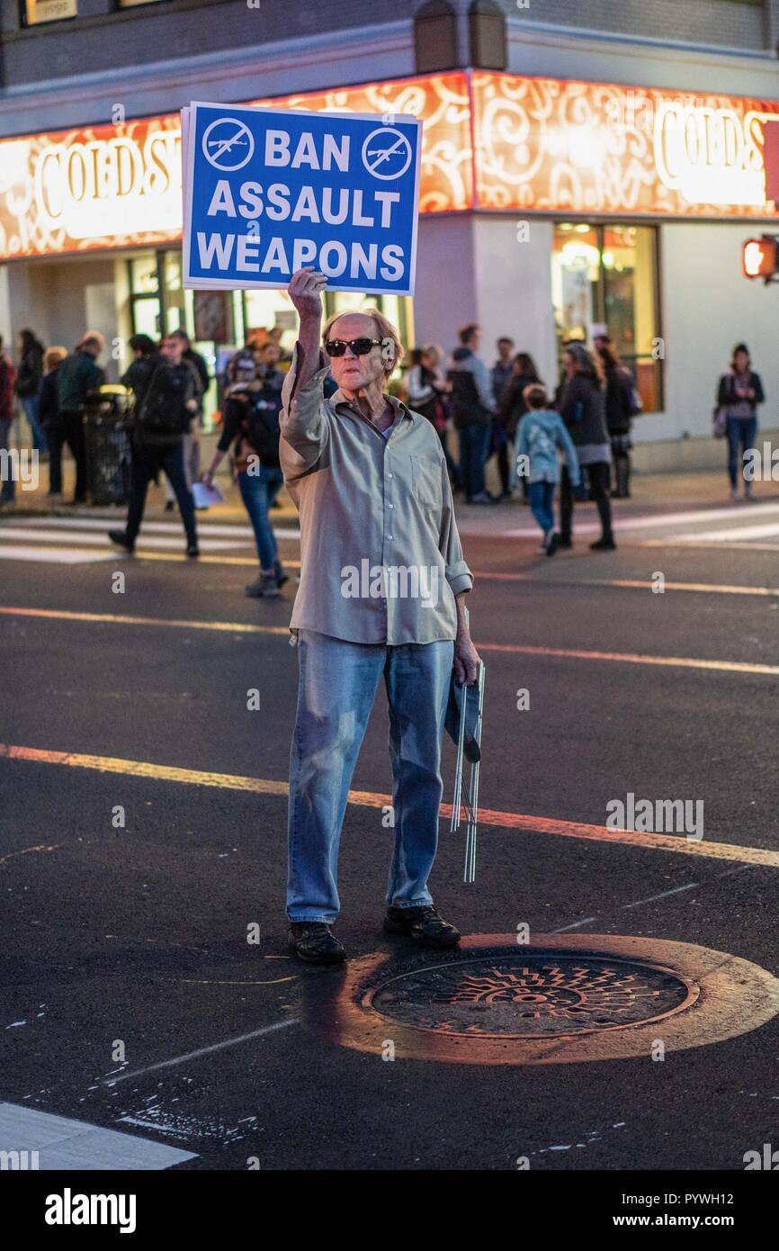 Protester holds sign to ban guns in a busy intersection. As President Trump arrives to pay his respects to the victims of the Tree of Life synagogue in Pittsburgh, hundreds took to the street marched and protested in solidarity to voice their concerns about Trump's policies and to stand up against hate of all kinds. Stock Photo