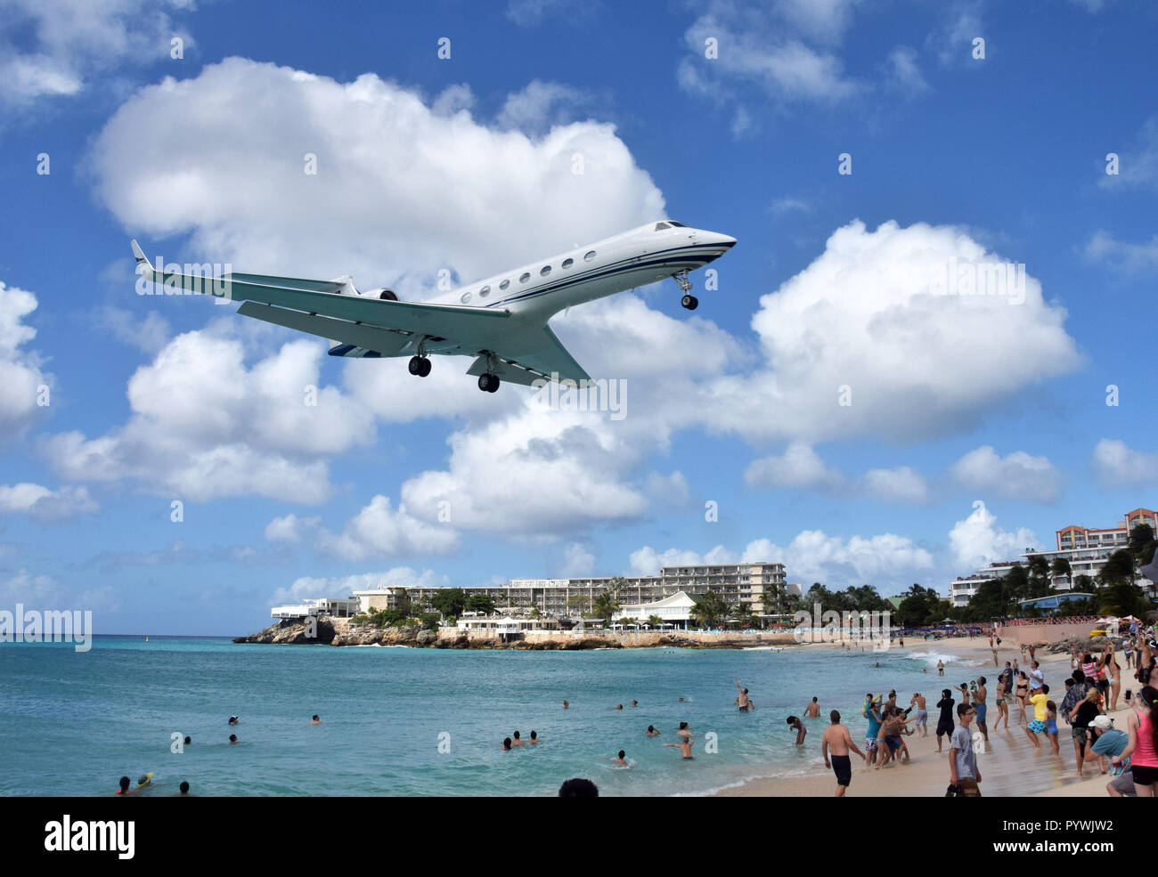 MAHO BEACH - ST MAARTEN: Jet lands low over the beach in St Maarten in the Caribbean on December 24, 2015 as tourists enjoy the landmark location Stock Photo