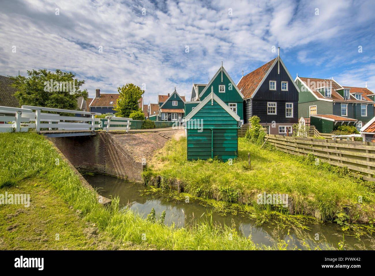 Characteristic Dutch village scene with colorful wooden houses and bridge with dike over canal on the island of Marken in the Ijsselmeer or formerly Z Stock Photo