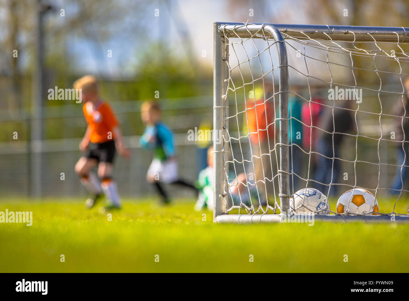 Modern aluminum soccer goal for youth with children training  in the background Stock Photo