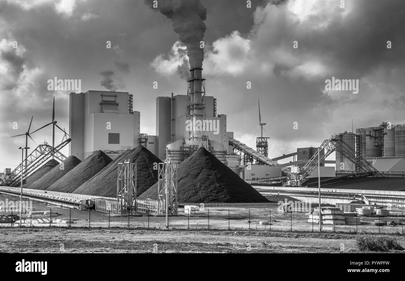 Heavy industry plant with pipes and smoke and piles of coal in black and white Stock Photo