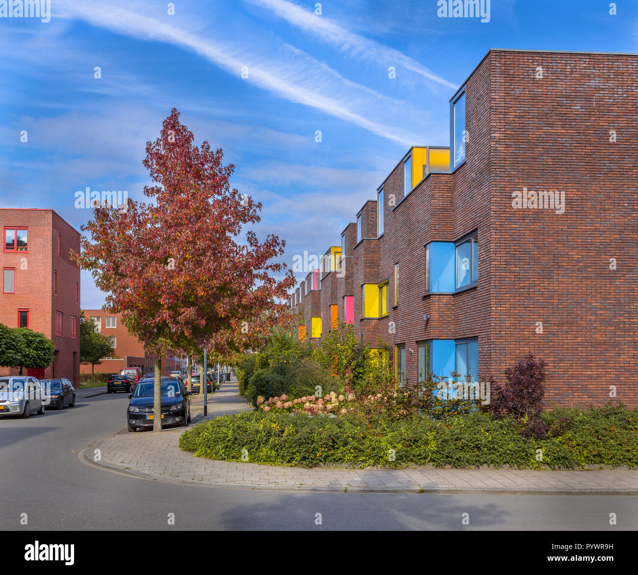 Block of Colorful modern suburban family apartments in a lively proper neighborhood with trees and gardens Stock Photo