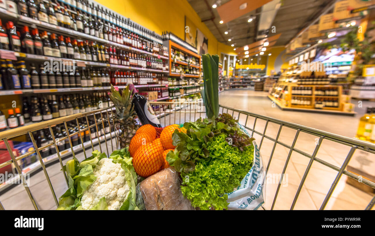 Grocery cart at a supermarket aisle filled up with healthy food products seen from the customers point of view Stock Photo