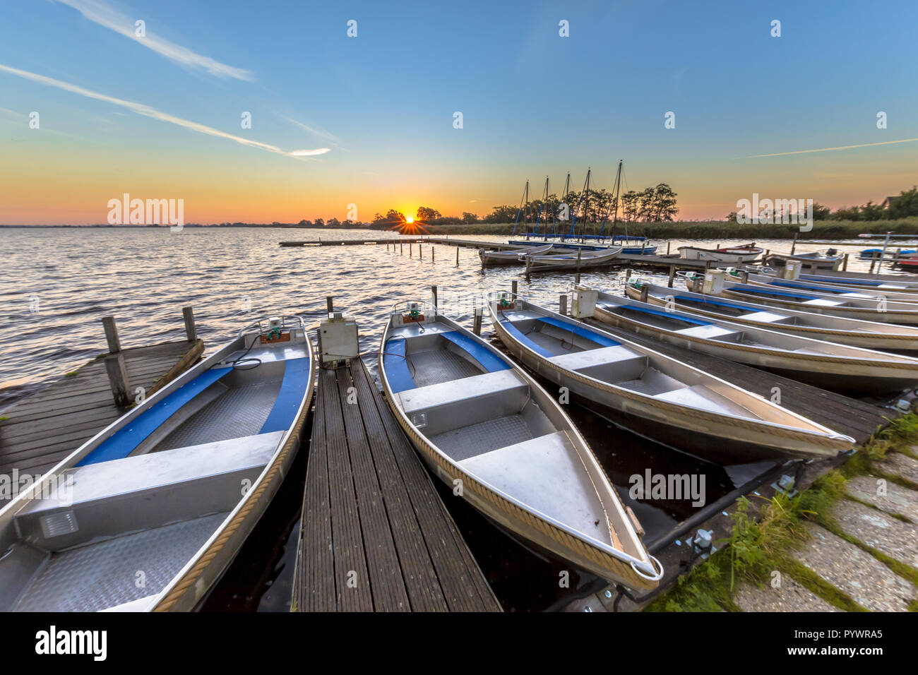 Row of rental boats in a dutch marina while the sun is rising over the horizon Stock Photo