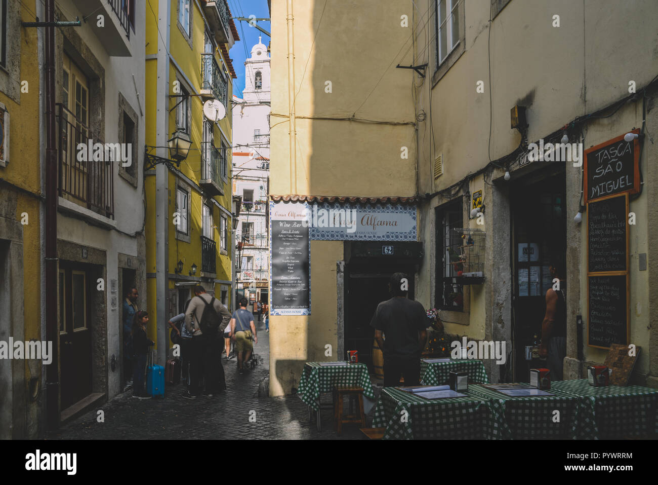 Lisbon, Portugal - Oct 24, 2018: Narrow streets with traditional restaurants in Alfama district of Lisbon with Sao Vicente church in background Stock Photo