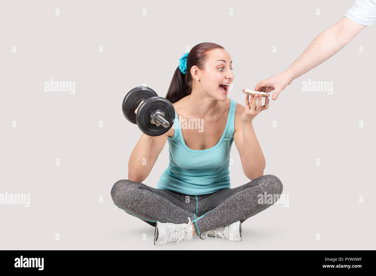 Fitness sports women holds a dumbbell and wants to eat a sandwich Stock  Photo - Alamy