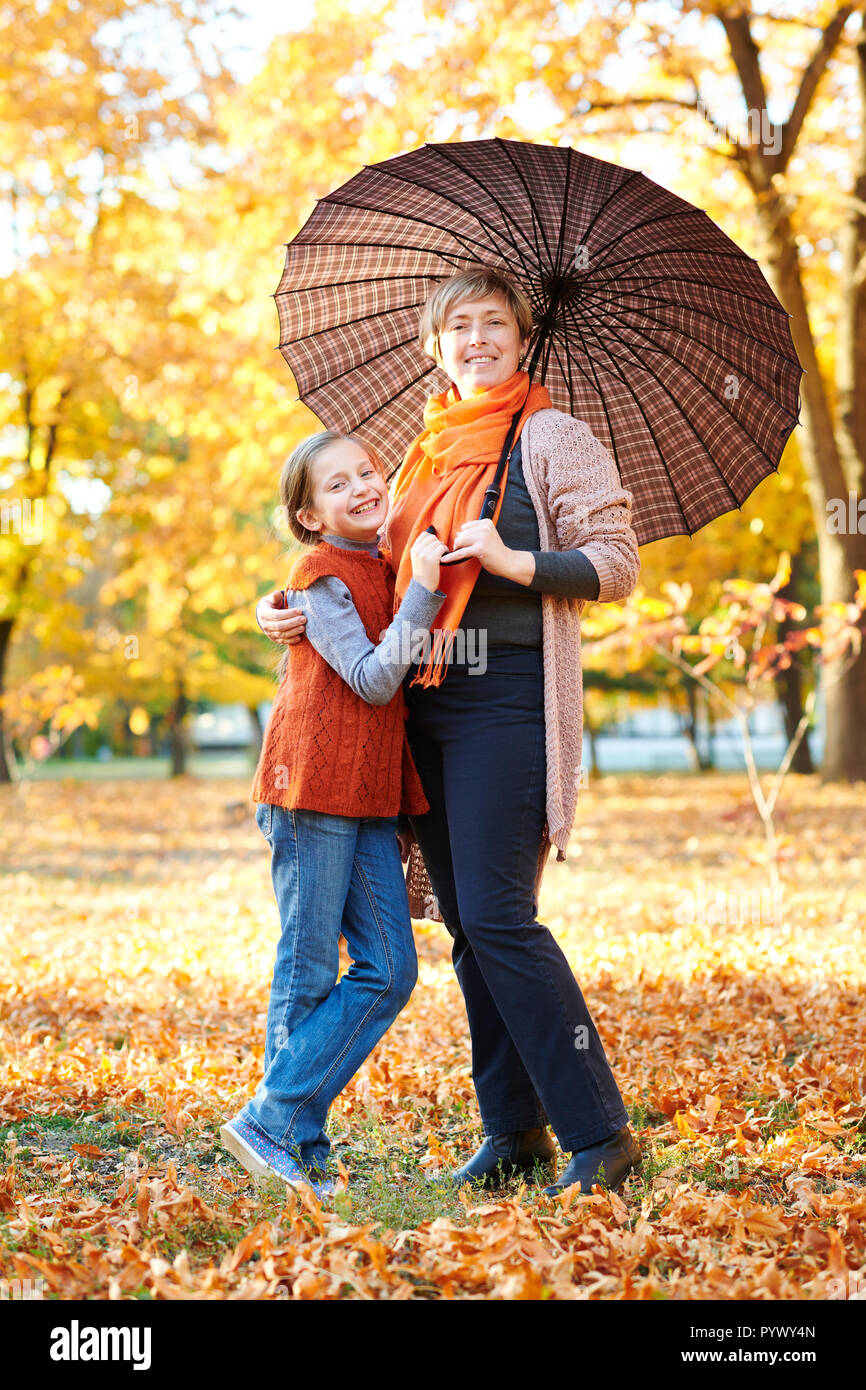 Mother and daughter are in autumn city park. Peoples are posing under ...