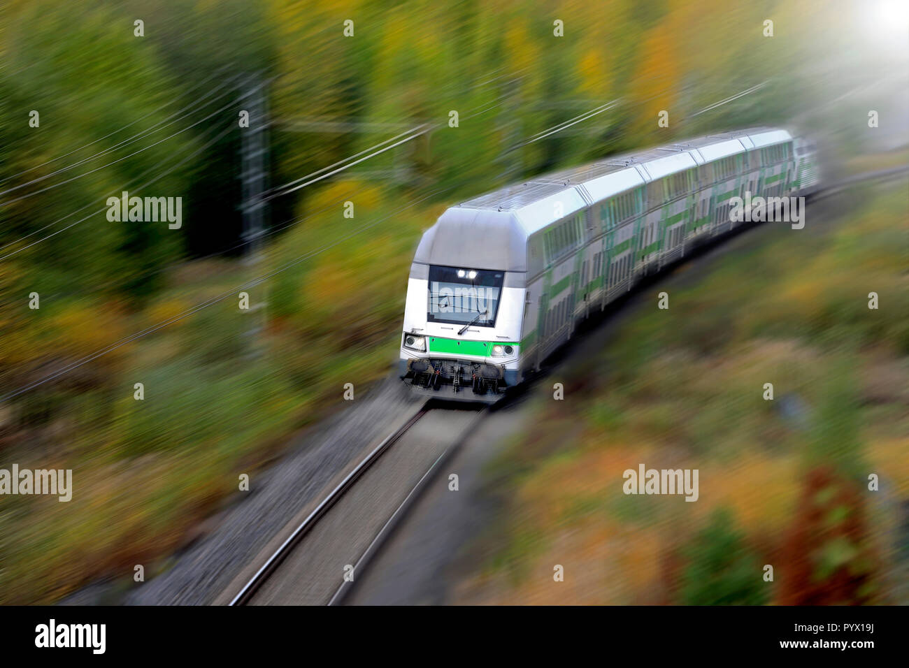 Passenger train at speed in autumn, elevated view, motion blur. Stock Photo