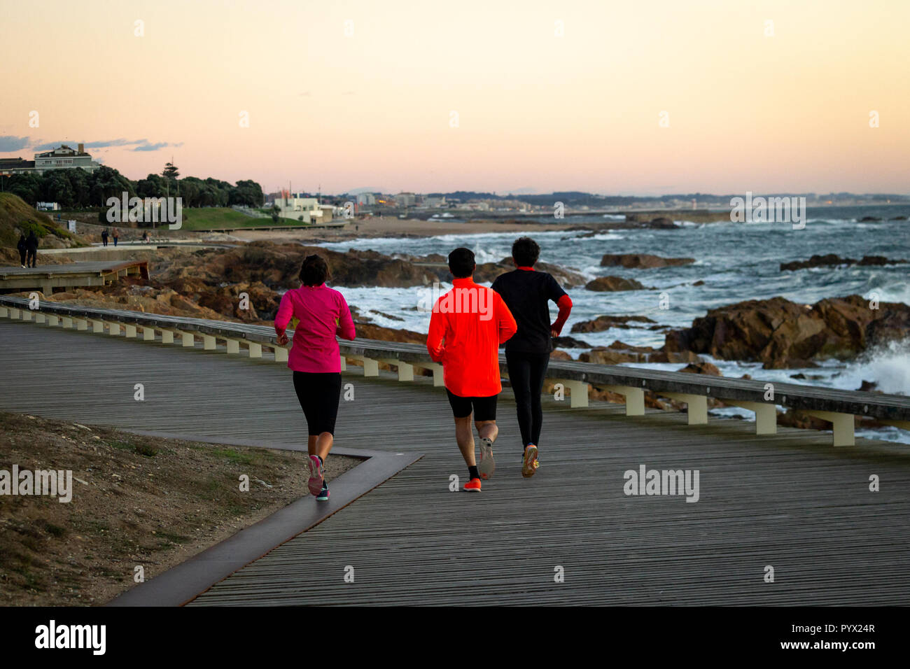 Three people run along the boardwalk. Back view. Stock Photo