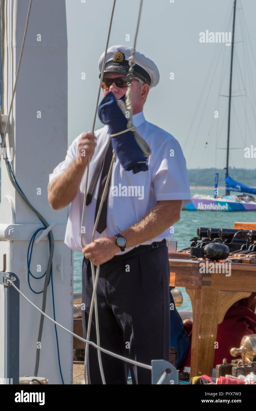 man hoisting signal flags to control yacht racing during the annual