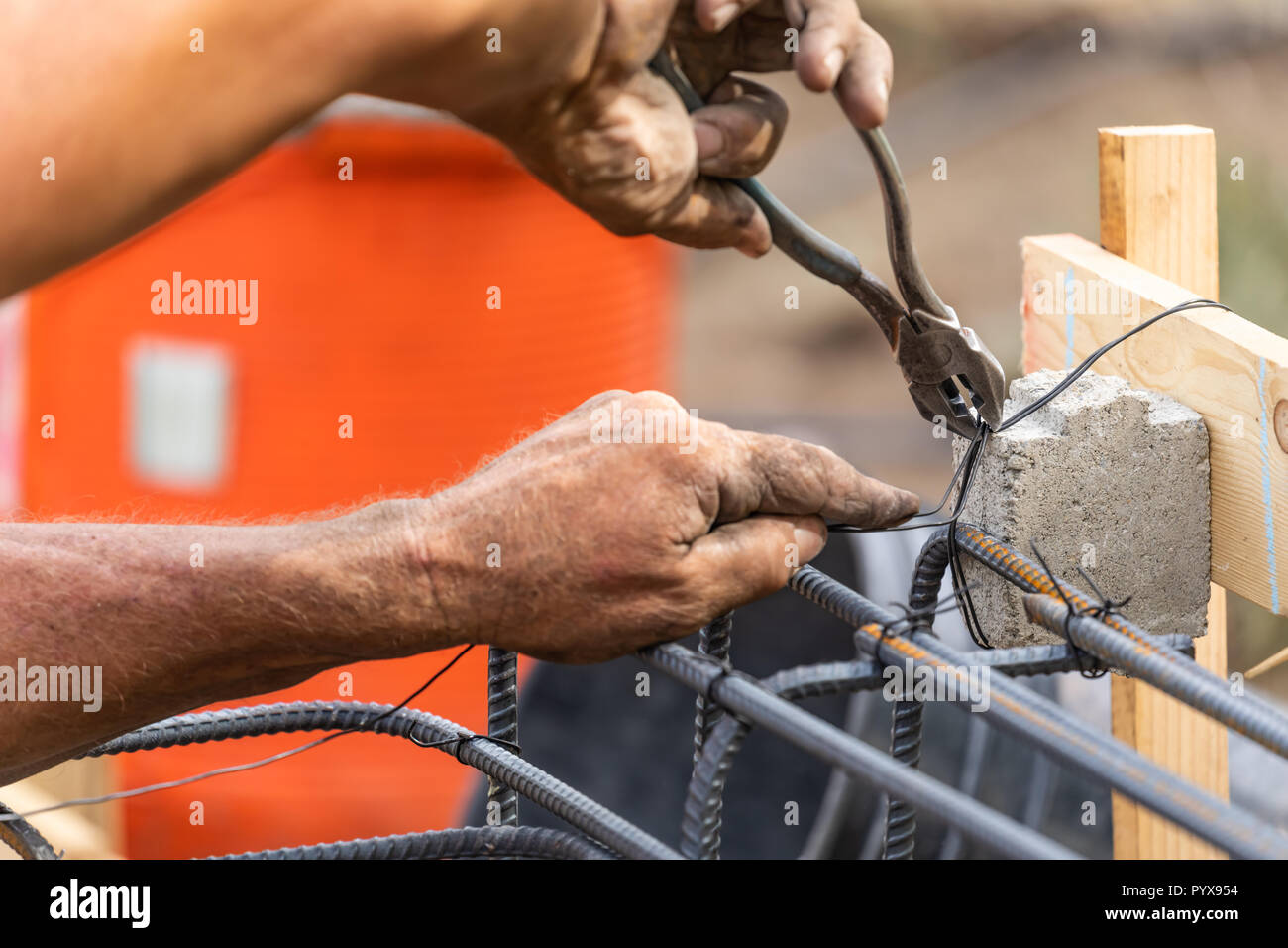Worker Securing Steel Rebar Framing With Wire Plier Cutter Tool At