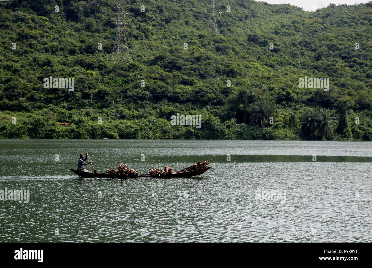 Man transports lumber on the Volta River in a long canoe, Akosombo, Ghana Stock Photo