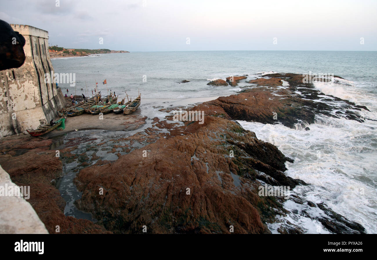 Fishermen and fishing boats at the base of Cape Coast Castle in Cape Coast, Ghana Stock Photo