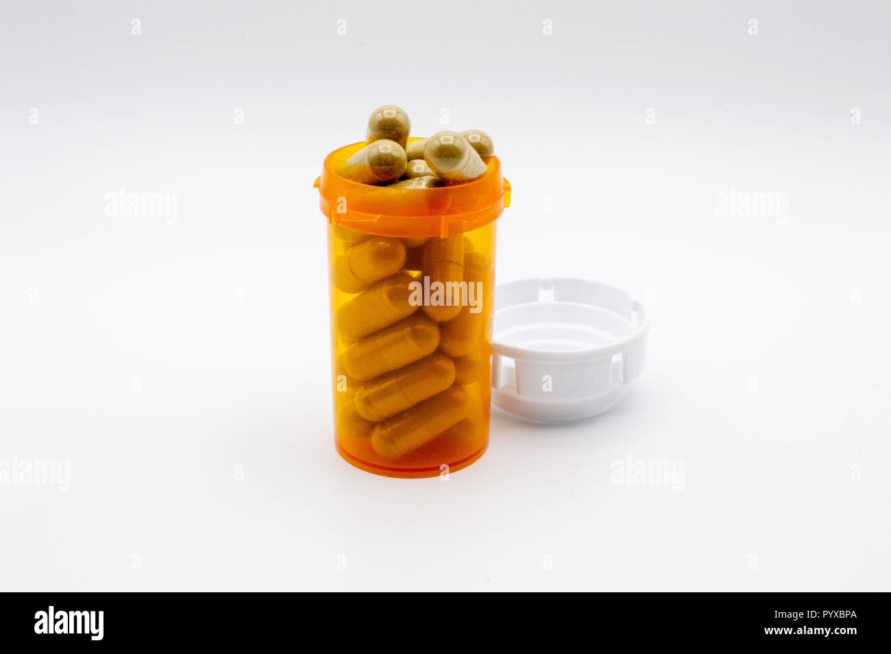 Green capsules of Maeng Da Kratom in yellow medicine bottle on white background. Stock Photo