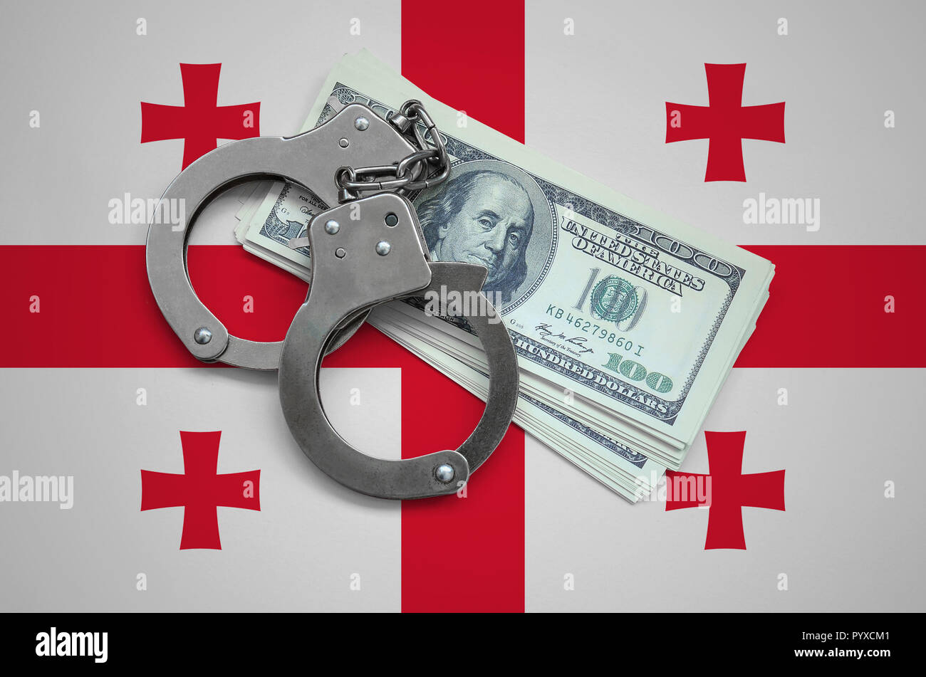 Georgia flag  with handcuffs and a bundle of dollars. Currency corruption in the country. Financial crimes. Stock Photo
