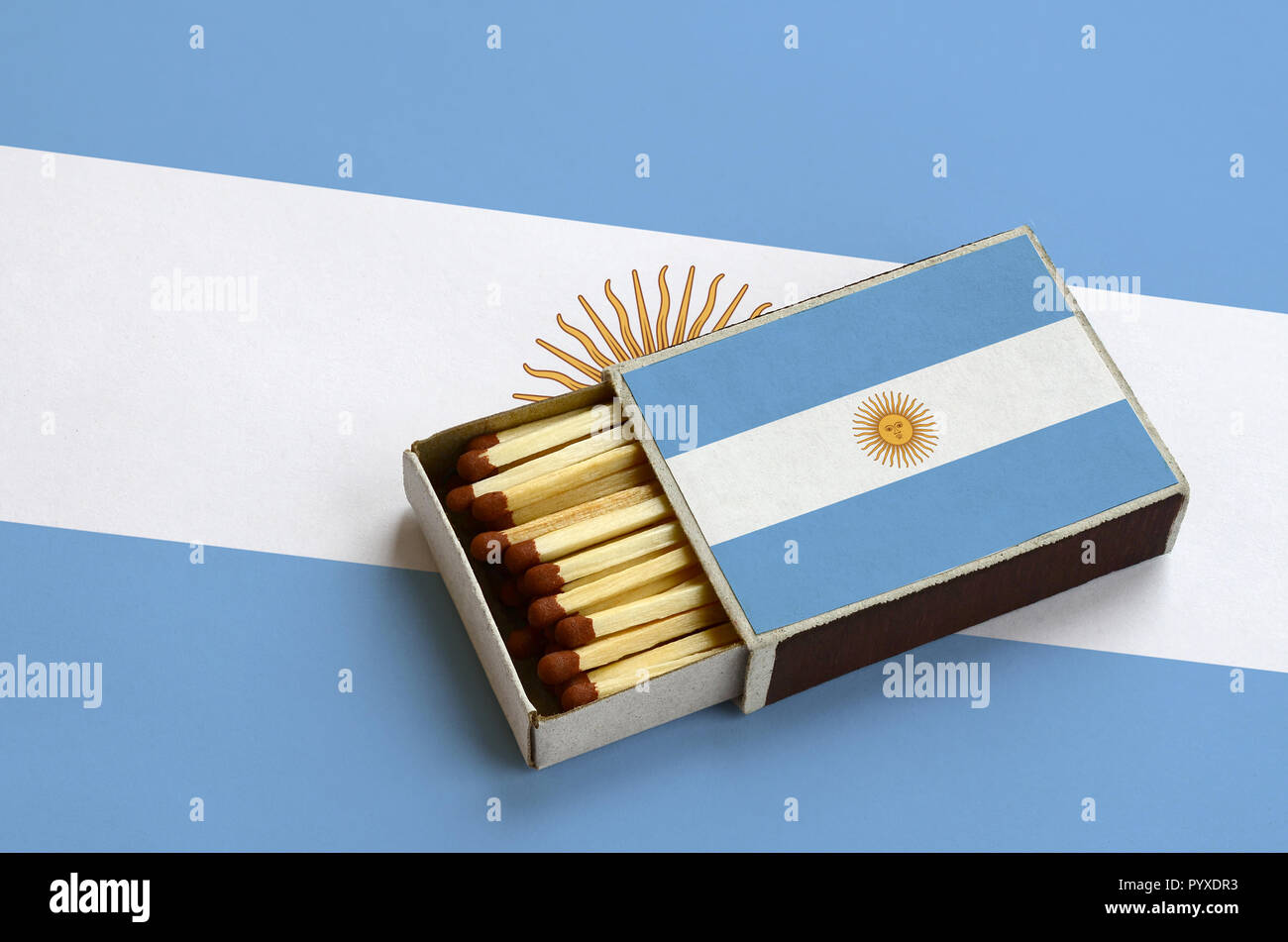 Argentina flag  is shown in an open matchbox, which is filled with matches and lies on a large flag. Stock Photo