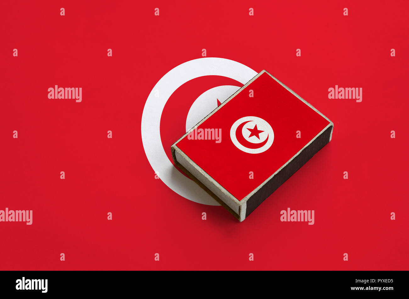 Tunisia flag  is pictured on a matchbox that lies on a large flag. Stock Photo