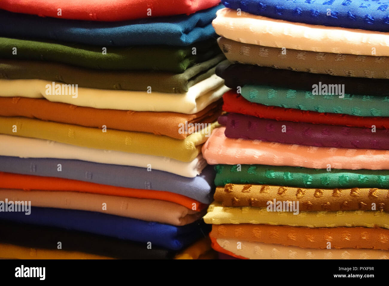 Stack with cloths and fabric in many different colours in one stall Stock Photo