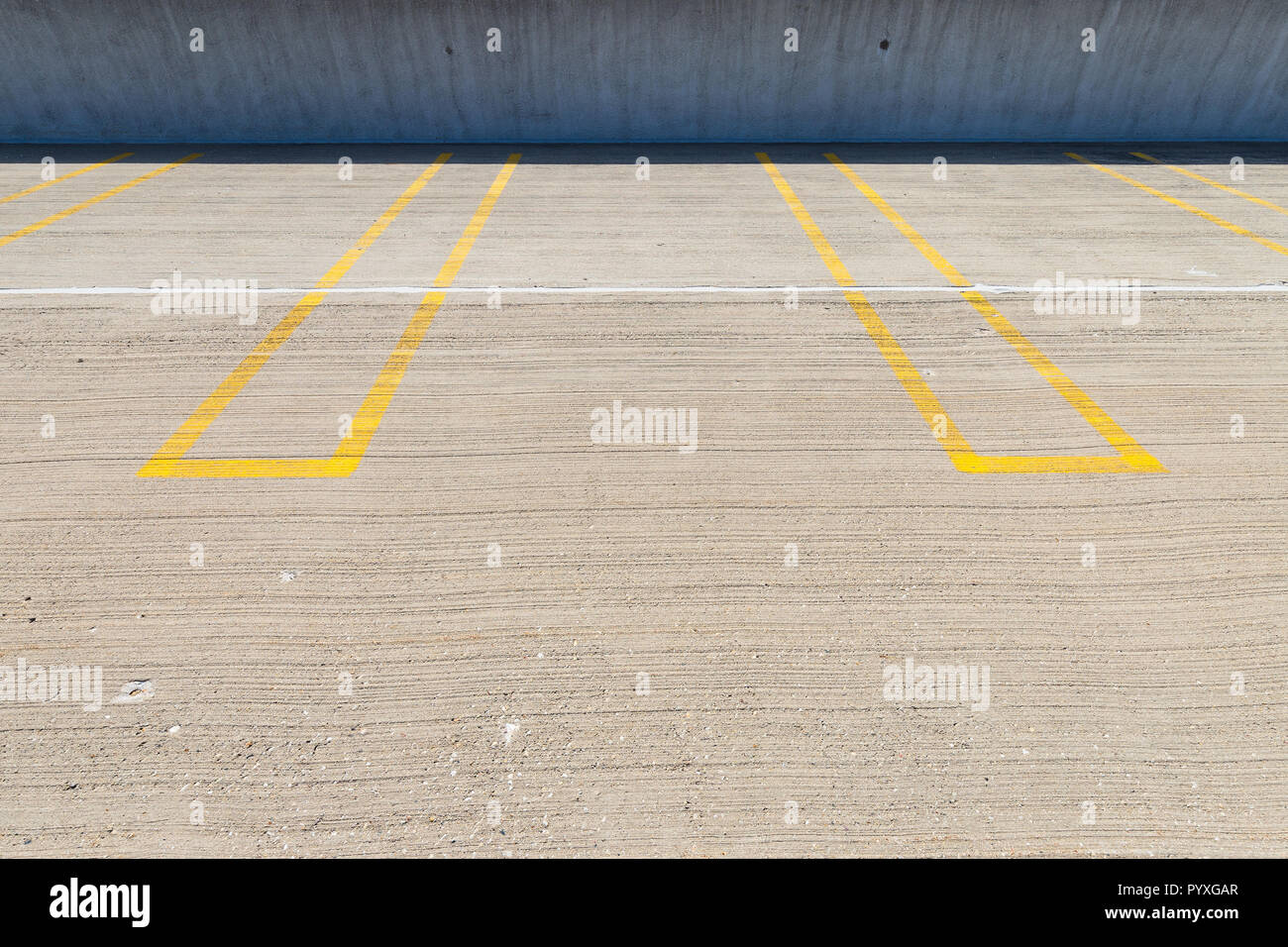 Empty parking spaces with yellow lines in a parking garage. Stock Photo