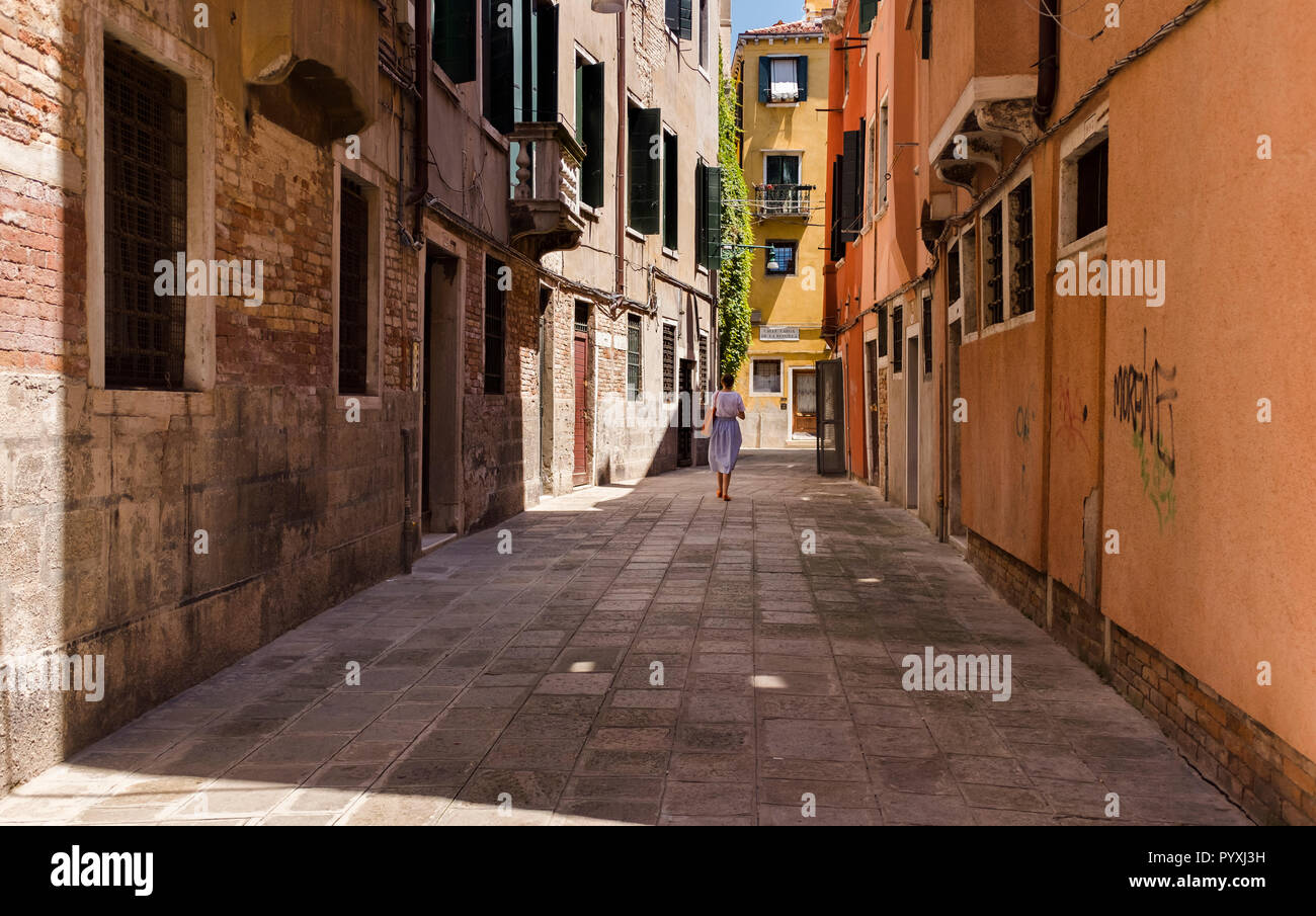 A woman walks down a quiet street in Venice, Italy Stock Photo