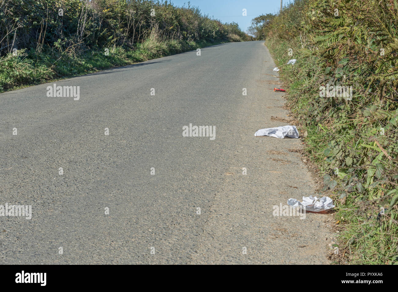 Stretch of litter-strewn country lane. Concept roadside litter UK. Keep Britain tidy, plastic waste in road. For Clean Up Britain campaign. Stock Photo