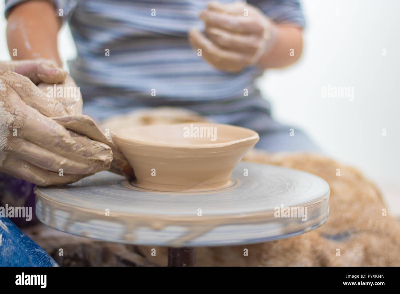 Ware from clay. The teacher helps the student to make clay dishes Stock Photo