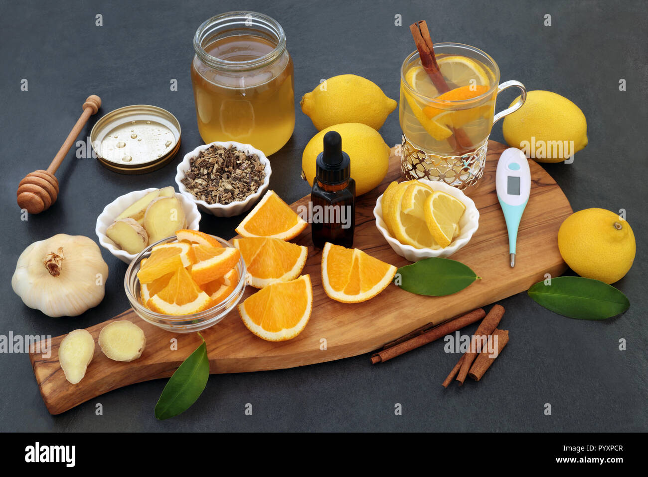 Alternative cold and flu remedy with thermometer, eucalyptus oil, fresh ginger, orange and lemon