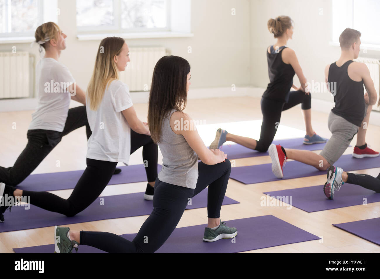 Group of people doing squat standing on rubber mats Stock Photo