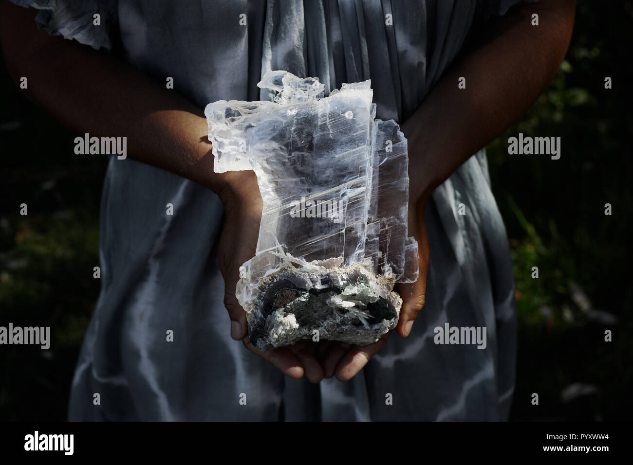 Close up of a woman holding a dark, powerful selenite crystal on geode Stock Photo
