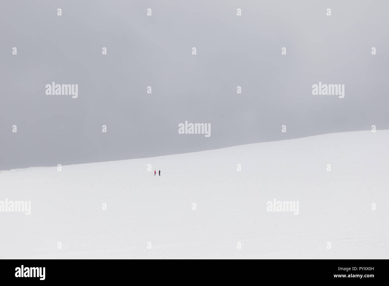 A very minimalistic view of two distant people over a mountain covered by snow Stock Photo