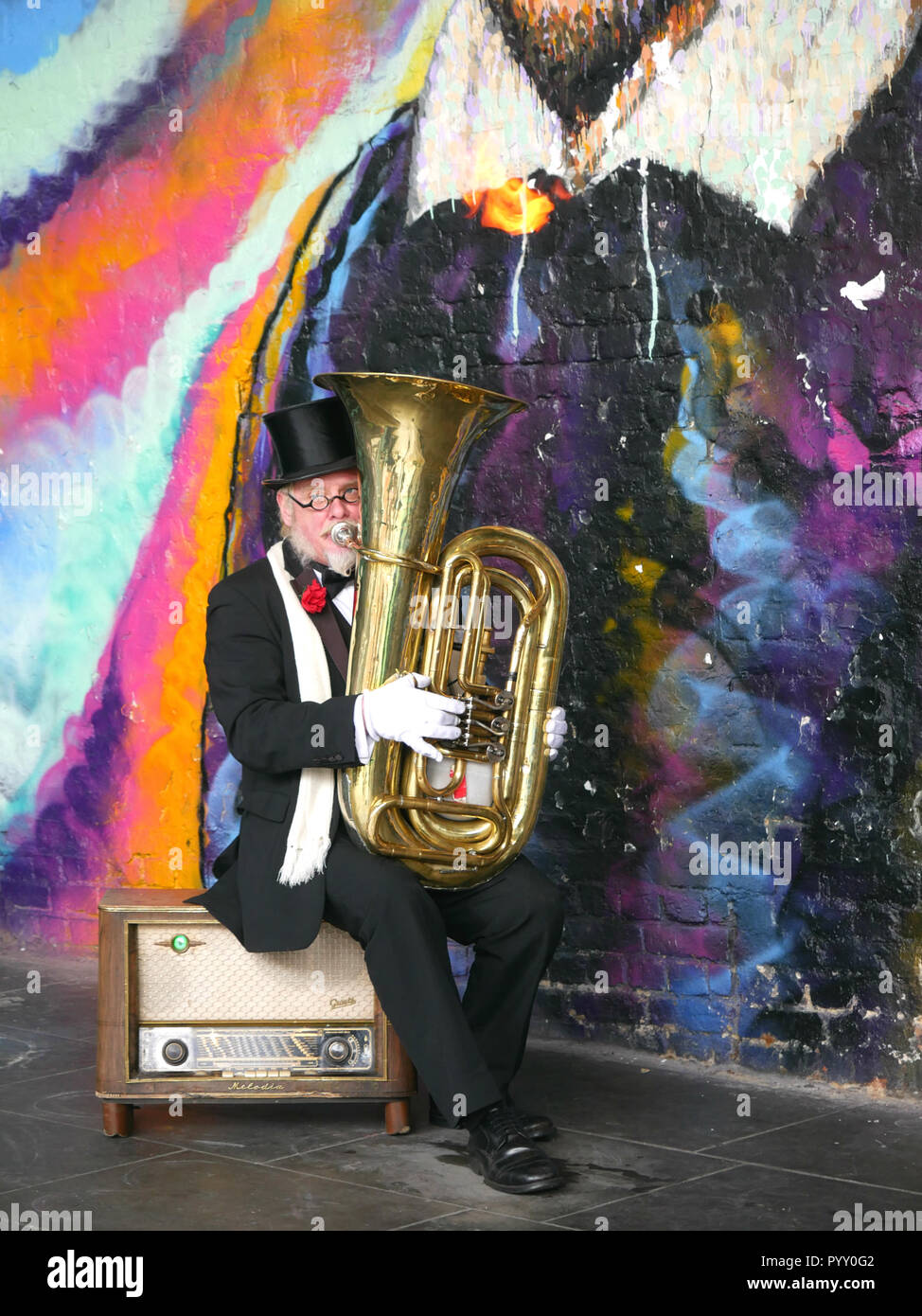 Elderly man playing a tuba shooting fire from the top Stock Photo
